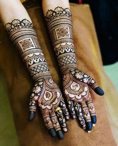 two hands with henna tattoos on them, one is showing off the intricate design