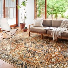 a living room filled with furniture and lots of windows next to a large rug on the floor