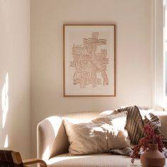 a living room filled with furniture and a painting hanging on the wall above it's windows