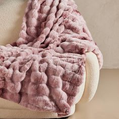 a pink blanket sitting on top of a white chair