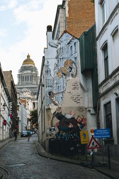 a street with buildings and graffiti on the side, along with people walking down it