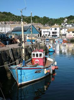 a small blue boat is docked in the water next to some houses and boats on the shore