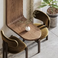 a wooden table with two chairs next to it and a potted plant in the corner