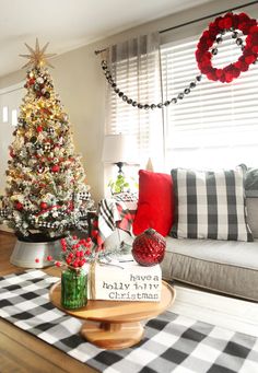 a living room decorated for christmas with red and white decorations on the tree, black and white checkered tablecloth