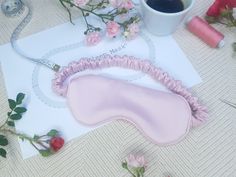 a pink eye mask sitting on top of a piece of paper next to some flowers