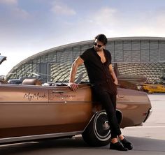 a man leaning on the back of a brown car