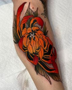 an orange flower with leaves on the side of a woman's leg is shown