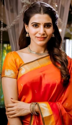 a woman in an orange and yellow sari with her arms crossed, smiling at the camera