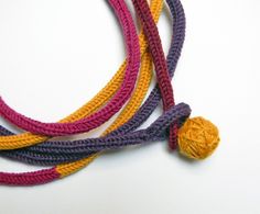 multicolored crochet necklace with yellow and purple beads on white table top