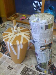 two paper cups sitting on top of a table covered in newspapers and other crafting supplies