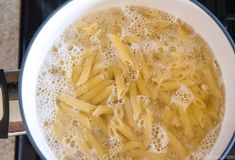 pasta being cooked in a pan on top of the stove with oil and water over it