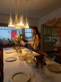 a woman standing at the end of a table with plates on it and balloons in the background