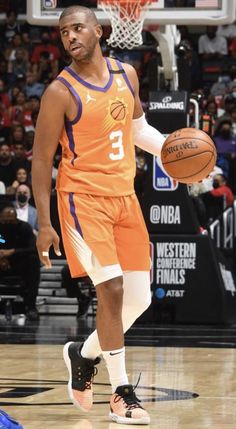 a man in an orange uniform holding a basketball on a court with people watching from the stands