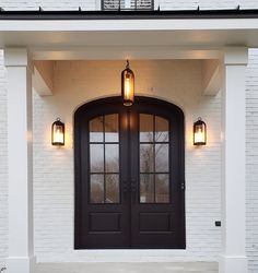 the front entrance to a home with two double doors and lights on either side of the door