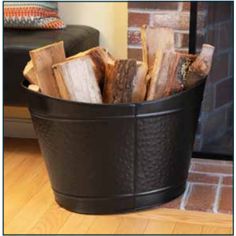 a black bucket filled with logs on top of a wooden floor