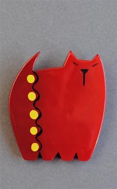 a red cat brooch with yellow dots on it