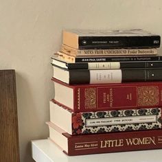 a stack of books sitting on top of a white table next to a wooden shelf