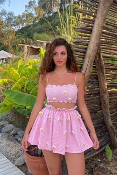 a woman standing next to a potted plant wearing a pink dress with daisies on it