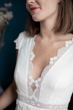 a woman wearing a white dress with lace on it