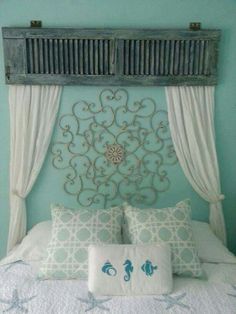 a bed with blue walls and white drapes on the headboard is decorated with an intricate iron work