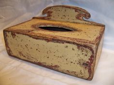 an old wooden box sitting on top of a white cloth covered tablecloth with a hole in the middle