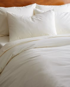 a bed with white sheets and pillows on it