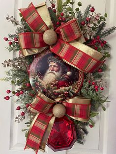 a christmas wreath hanging on the door with a santa clause face and red plaid ribbon