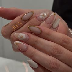 a woman's hands with french manies and gold decorations on them, holding onto her nails