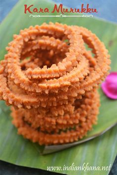 some kind of food on a green leaf with pink flowers in the background and text that reads kar a murukku