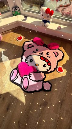 a pink teddy bear rug sitting on top of a wooden floor next to a window