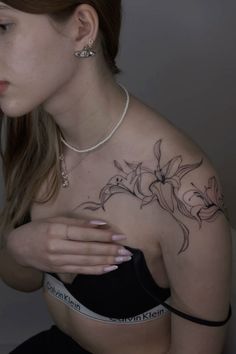 a woman with a tattoo on her chest holding onto her arm and looking down at the camera