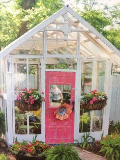 a small greenhouse with potted plants and flowers on the front door is painted pink