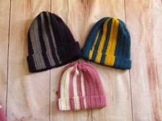 three knitted hats sitting on top of a wooden floor