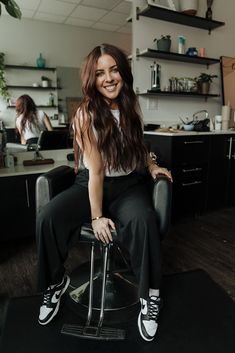 a woman sitting on top of a chair in a hair salon with her legs crossed