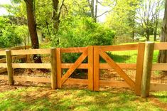 a wooden gate in the middle of a grassy area