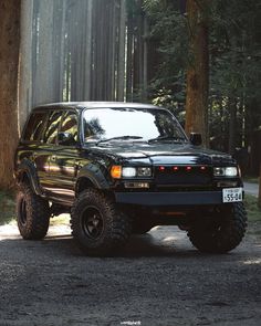 a black suv is parked in the woods