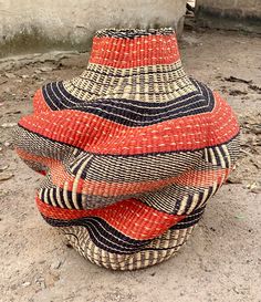 a woven basket sitting on the ground in front of a building with no doors or windows