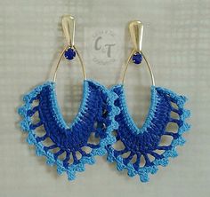 crocheted blue earrings hanging from hooks on a white surface with the letter c in gold