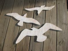 three wooden birds sitting on top of a wooden floor next to each other in flight