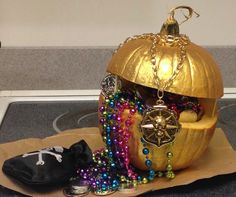 a gold pumpkin decorated with beads and other items on top of a table next to a black bag