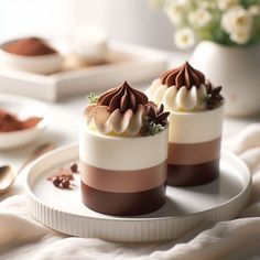 two desserts are sitting on a plate with spoons and flowers in the background