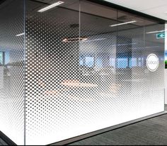 an office cubicle with glass walls and white dots on the wall, along with carpeted flooring