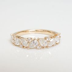 a yellow gold ring with five pear shaped diamonds on it's sides, set against a white background