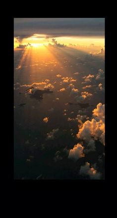 the sun is setting over some clouds in the sky as seen from an airplane window