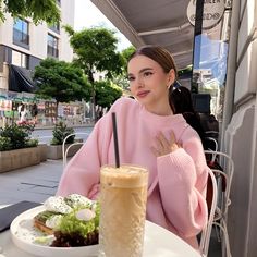 a woman sitting at a table in front of a plate of food with a drink