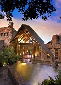 an outdoor hot tub in front of a stone building at dusk with lights on the windows