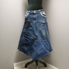 "Upcycled denim patchwork skirt with frayed seams for a distressed look. Decorative metal studs on pockets. Waist measures 32\" and length is approximately 29\"." Recycled Denim Patchwork Denim Skirt, Recycled Denim Patchwork Skirt, Denim Blue Patchwork Skirt From Recycled Denim, Patchwork Denim Skirt In Recycled Denim Blue, Recycled Denim Blue Skirt With Patchwork, Medium Wash Denim Skirt With Patchwork, Dark Wash Denim Skirt With Patchwork, Bohemian Dark Wash Denim Skirt, Bohemian Denim Patchwork Skirt