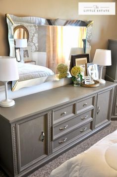 a bed room with a large gray dresser and a mirror on the wall above it