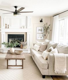 a living room filled with furniture and a fire place under a ceiling fan in front of a fireplace