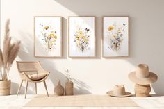 three paintings hang on the wall above a chair and two vases filled with flowers